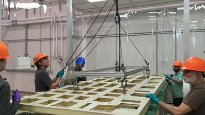 people standing around and lifting a large CRP in a clean room tent.