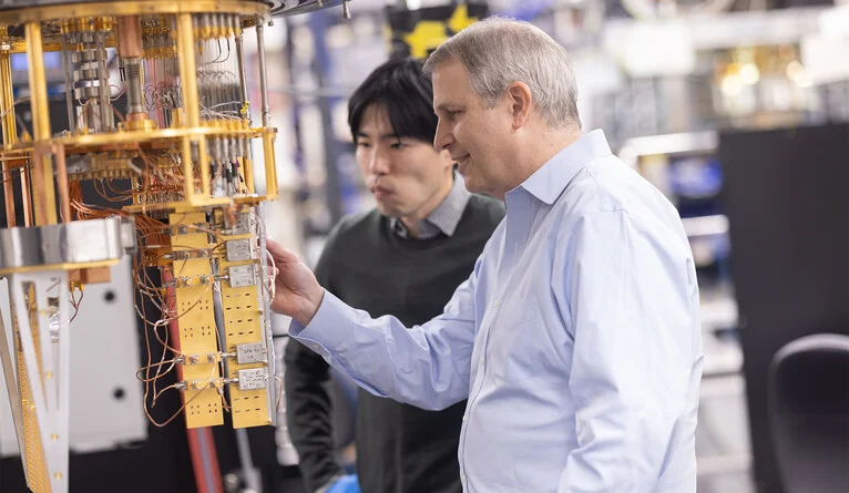 Schoelkopf, in the lab, examines one of the special refrigerators that researchers use to chill superconducting quantum devices down to near absolute zero for experiments. (Photo by Dan Renzetti)