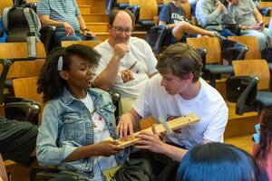 two people playing an instrument with another watching